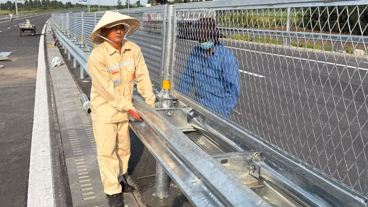 Công nhân kiểm tra, hoàn thiện lưới gắn lan can trên cao tốc trước giờ thông xe. Ảnh: QUÝ HIỀN.