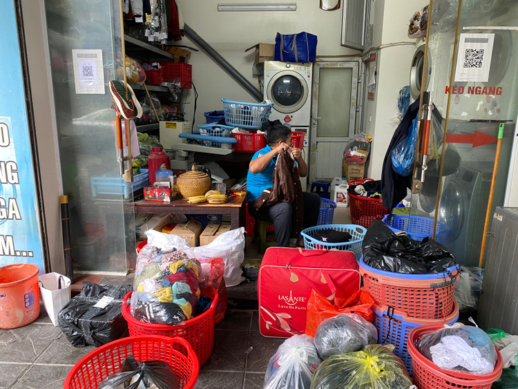 Tiệm giặt sấy của anh Hùng trên đường Dương Khuê quần áo chất đống chờ đến lượt giặt.