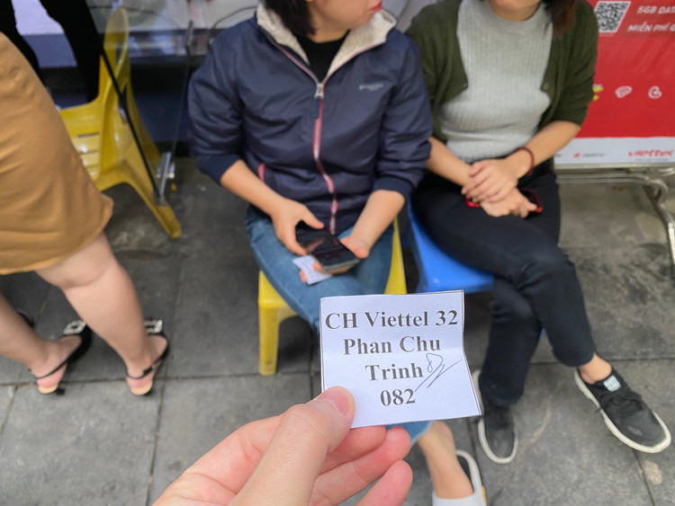 Nếu đến trực tiếp các điểm giao dịch, người dùng di động sẽ được phát số thứ tự và mất một khoảng thời gian chờ đợi trước khi gặp nhân viên chăm sóc khách hàng. Sau đó, họ sẽ được hướng dẫn điền thông tin để tiến hành cập nhật, chuẩn hóa thuê bao. Những chiếc ghế được xếp cả bên ngoài cửa để người dân ngồi đợi. - Ảnh: T.Huy