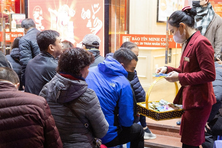 Nhân viên cửa hàng hướng dẫn khách xếp thành hàng ngay ngắn và phát phiếu mua hàng - Ảnh:phunuvietnam