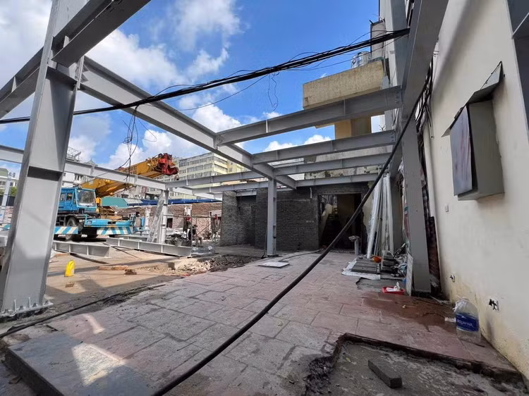 Công trình được đào móng, đổ trụ cột bê tông mới và lắp đặt khung dầm thép tầng một. Phần tường nhà ở một vị trí cũng được xây mới.