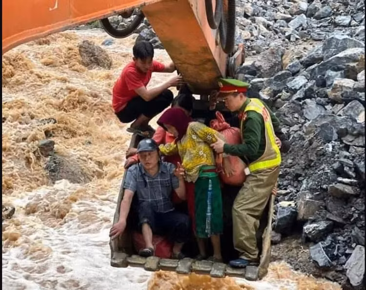 Thượng úy Tường và người dân phải ngồi trong gầu máy xúc để thoát khỏi khu vực nguy hiểm. Ảnh: Công an Nhân dân.