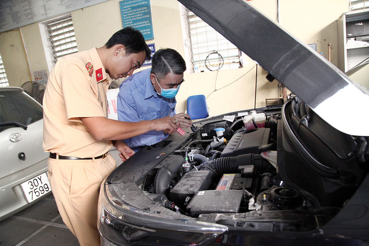 Đại úy CSGT Trần Vĩnh Phúc cùng nhân viên đăng kiểm đang thực hiện quy trình kiểm định xe cơ giới.