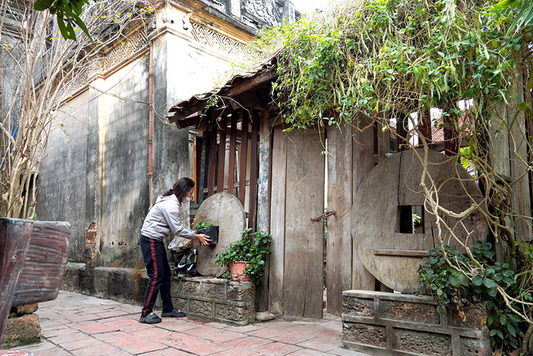 Chị Nguyễn Thị Hồng Thúy bên ngôi nhà của bố đẻ để lại. Đây cũng là một ngôi nhà cổ có bậc thềm, chân tường bằng đá ong cùng cánh cửa bằng gỗ rất lạ.