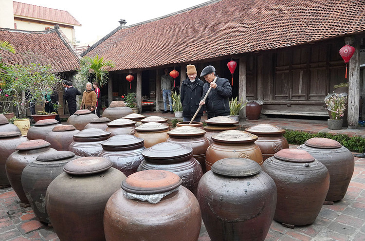 Ông Hà Hữu Thể đang kiểm tra chất lượng những chum tương, ngôi nhà cổ của ông gồm 7 gian và còn tương đối nguyên vẹn. Đây cũng là một trong số ít gia đình còn giữ nghề làm tương nếp truyền thống.