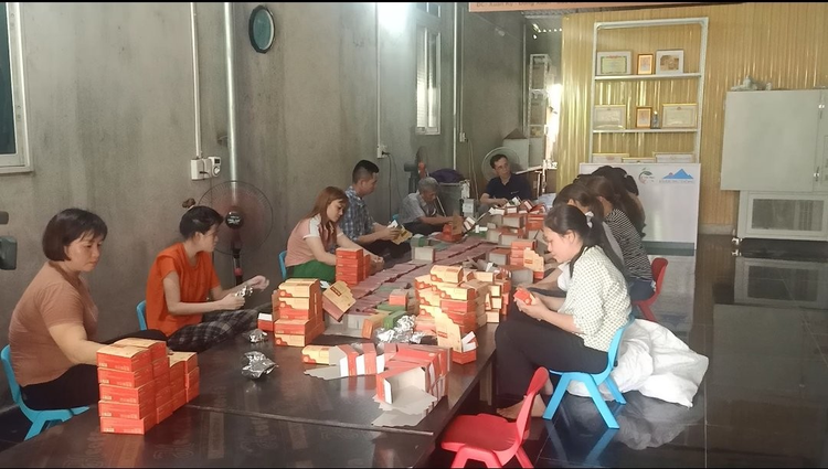 Chị Bùi Thị Hưng (ngoài cùng bên trái) đóng gói và dán nhãn trà tại nhà xưởng.