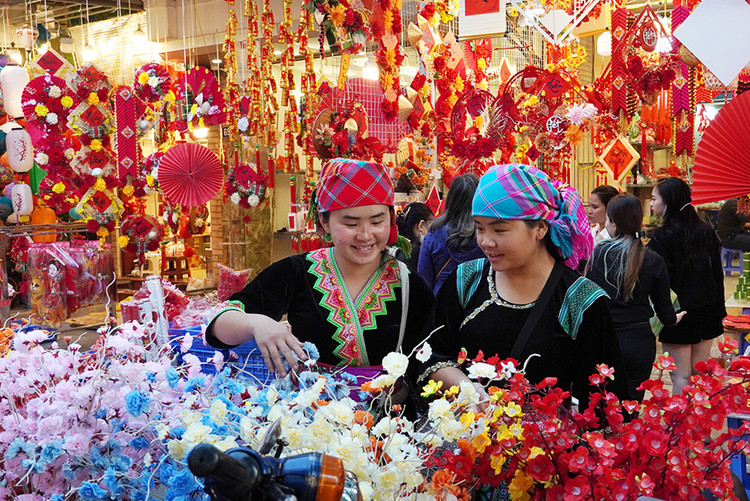 Hai em gái người dân tộc H" Mông tỏ ra rất thích thú bên một gian hàng hoa nhựa.