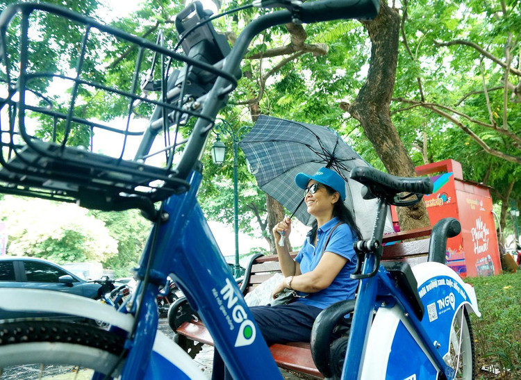 Cơn mưa bất chợt ào tới khiến chị Anh Thư tạm dừng đạp xe thưởng cảnh Hà Nội chớm Thu.