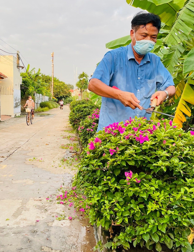 Ông Huy cắt tỉa cây, chăm sóc hoa, làm đẹp cảnh quan môi trường.