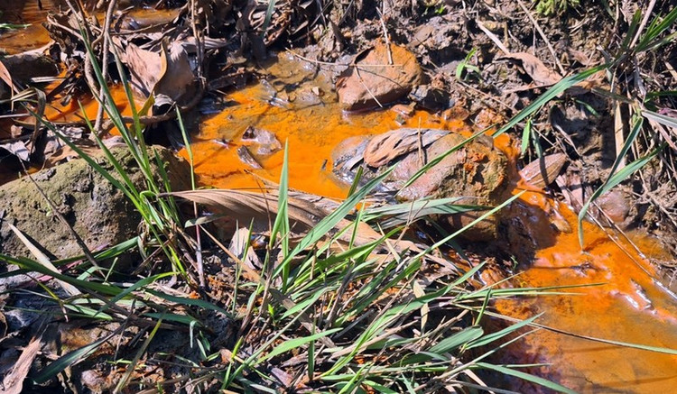 Một dòng nước gần khu vực mỏ than màu đục, đỏ đổ ra hướng suối Vọ.