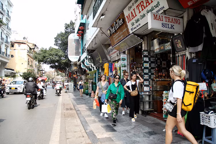 Du khách nước ngoài thả bộ mua sắm trên vỉa hè phố Hàng Gai.