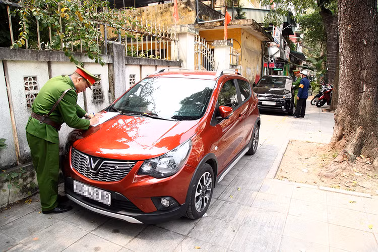 Các đồng chí công an phường Nguyễn Du đang lập biên bản với những chiếc xe ô tô đỗ trên vỉa hè.