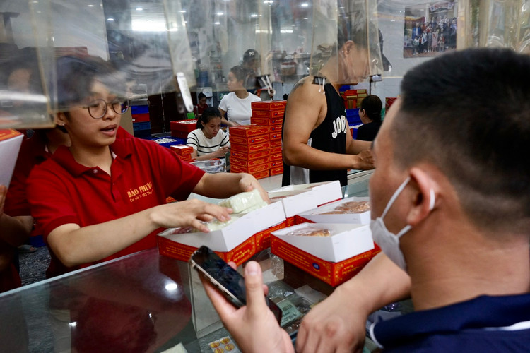 Một hộp 4 bánh gồm 2 bánh dẻo, 2 bánh nướng. Nhân viên bán hàng đang xếp bánh vào hộp.