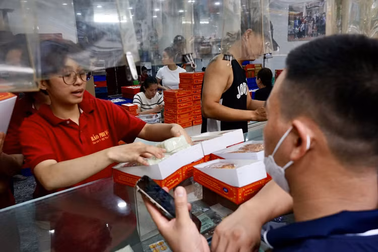 Một hộp 4 bánh gồm 2 bánh dẻo, 2 bánh nướng. Nhân viên bán hàng đang xếp bánh vào hộp.