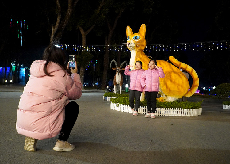 Hai bé Minh Anh và Minh Châu, 8 tuổi nhà ở Lĩnh Nam tỏ ra rất thích thú khi chụp ảnh cùng với linh vật mèo trong công viên Thống Nhất.