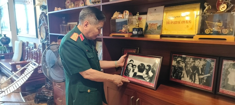 Trung tướng Phạm Xuân Thệ bên những bức ảnh lưu lại khoảnh khắc không thể nào quên. Ảnh: Mai Loan.