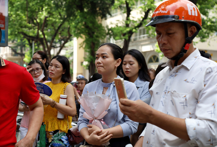 Bó hoa trên tay, nét mặt đầy lo âu, chị Thảo đang đợi tiếng trống hết giờ thi của con gái Thảo Vi.
