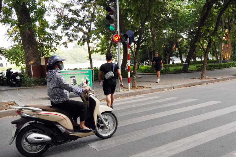 Khi bấm nút sang đường nên kiên trì chờ đèn chuyển màu xanh, không nên băng qua đường như người đàn ông trong ảnh.