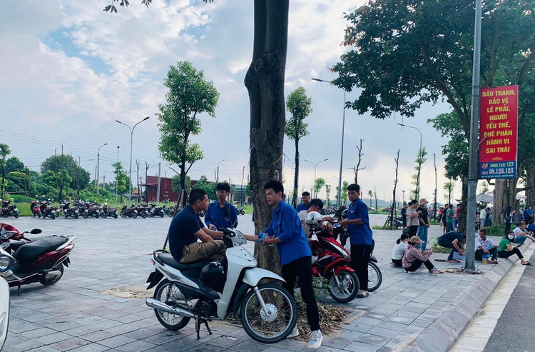 Đoàn thanh niên phân phát nước cho các bậc phụ huynh chờ đón con tại địa điểm thi.