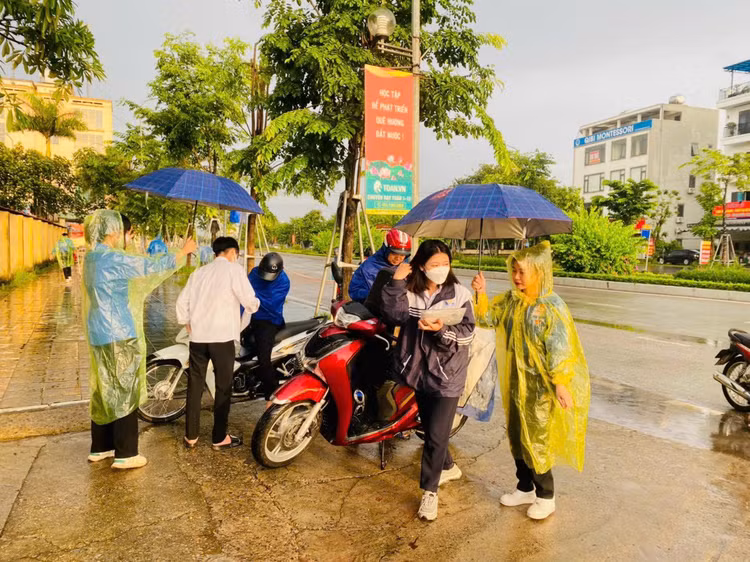 Không quản ngại mưa gió, những màu "áo xanh" hăng say, miệt mài che ô cho thí sinh vào phòng thi.