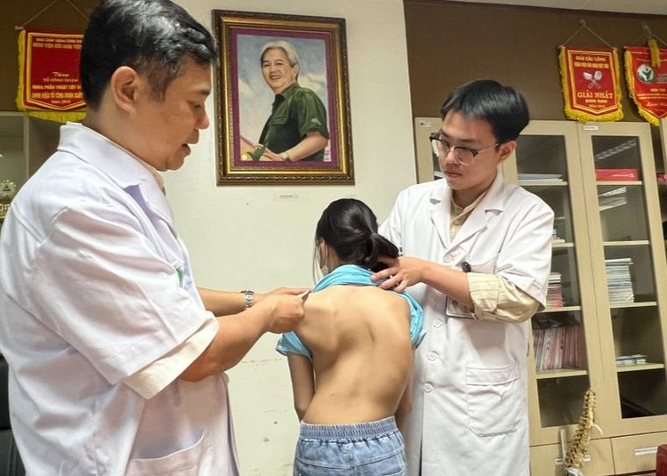 PGS.TS Đinh Ngọc Sơn khám cho cháu bé 12 tuổi bị vẹo cột sống nặng. Ảnh Sức khoẻ và Đời sống