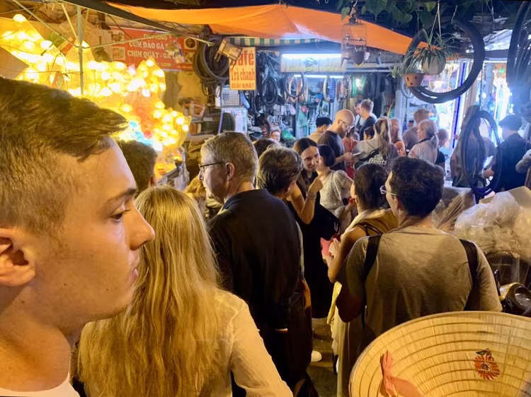 Đông đảo du khách nước ngoài kiên nhẫn xếp hàng đợi đến lượt trong ngõ nhỏ cạnh đường tàu trên phố Trần Phú tối ngày 21/8.