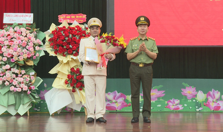 Thứ trưởng Trần Quốc Tỏ trao Quyết định và tặng hoa chúc mừng Thượng tá Y San ADrơng tại buổi lễ.