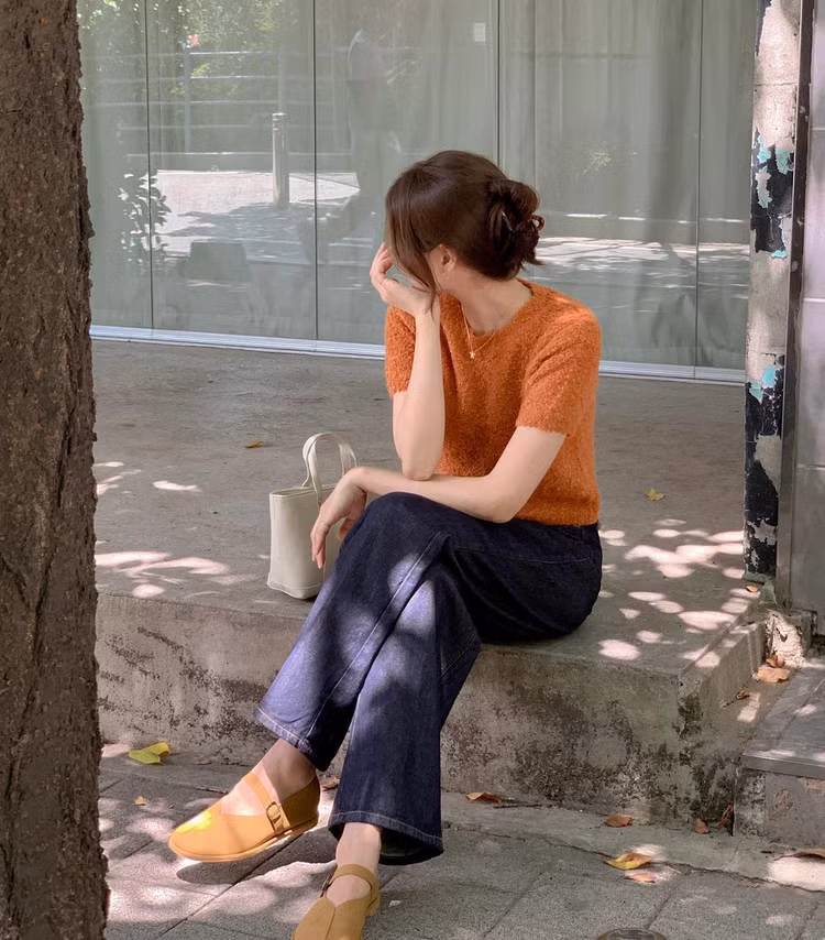 Kết hợp áo len cộc tay màu cam với quần jeans xanh tím than, người mặc có được bộ trang phục nổi bật, tươi tắn mà vẫn có sự hài hòa.