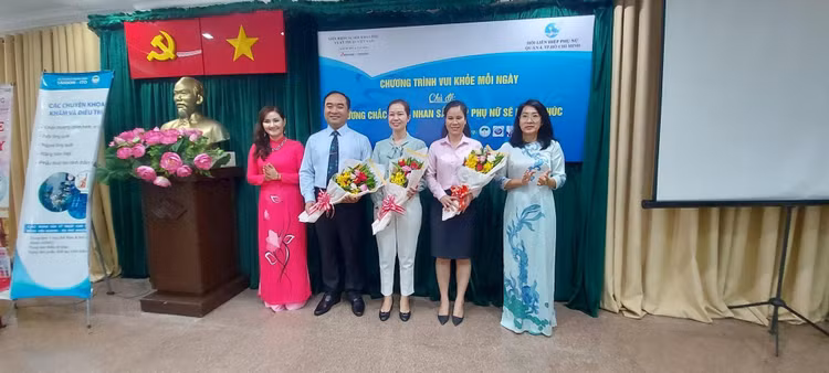 Nhà báo Bùi Hương và bà Lê Thị Diễm Huỳnh, Chủ tịch Hội Liên hiệp Phụ nữ Quận 4 (ngoài cùng bên phải) trao hoa cho PGS.TS.BS Phạm Hiếu Liêm và ThS.BS Nguyễn Thị Thùy Linh cùng đại diện Hệ thống Bệnh viện Sài Gòn - ITO (người thứ hai bên tay phải).