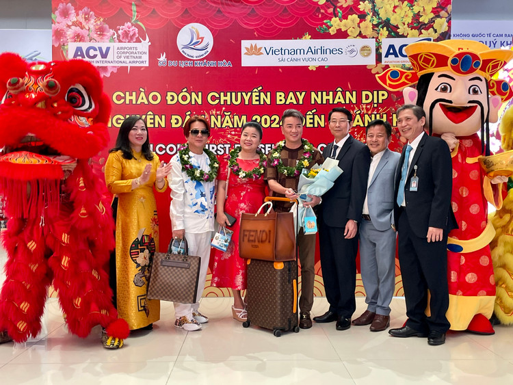 Phó Chủ tịch UBND tỉnh Đinh Văn Thiệu (áo đen giữa) và lãnh đạo các sở, ngành, đơn vị chào mừng những vị khách đầu tiên đến Khánh Hòa trên chuyến bay của Vietnam Airlines ngày đầu Xuân Giáp Thìn 2024 - Ảnh: Phạm Giang