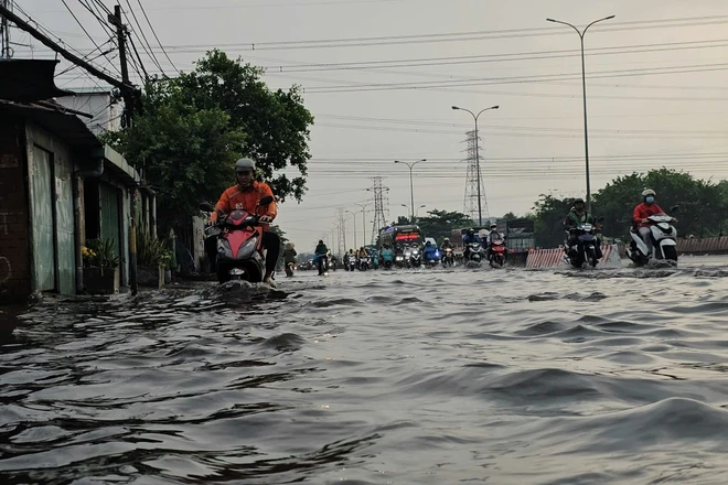 Người dân TP HCM bì bõm trong nước ngập sau mưa trái mùa kéo dài