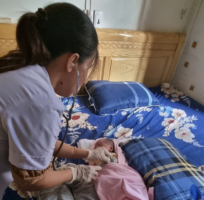 Cán bộ y tế kiểm tra sức khoẻ cho cháu bé.