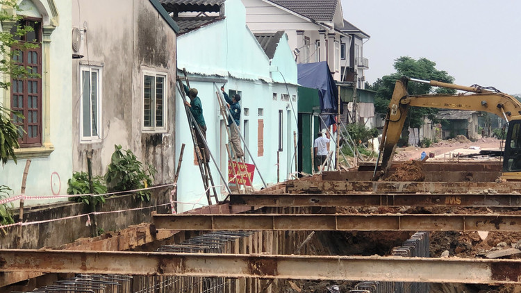 Công nhân đang dựng sắt hộp chằng chống tường nhà gia đình ông Chiến để tránh đổ sập.