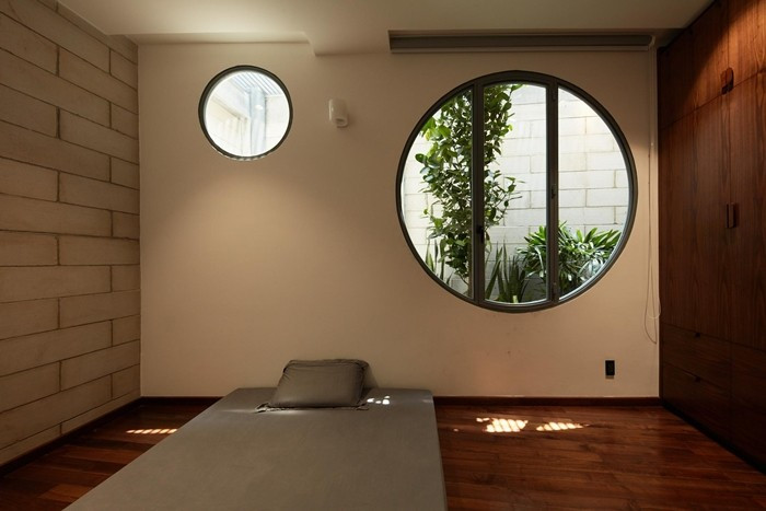 Các phòng ngủ phụ có cửa sổ tròn mở ra bồn cây xanh, đưa thiên nhiên vào từng góc nhỏ. Ảnh: Thiết Vũ