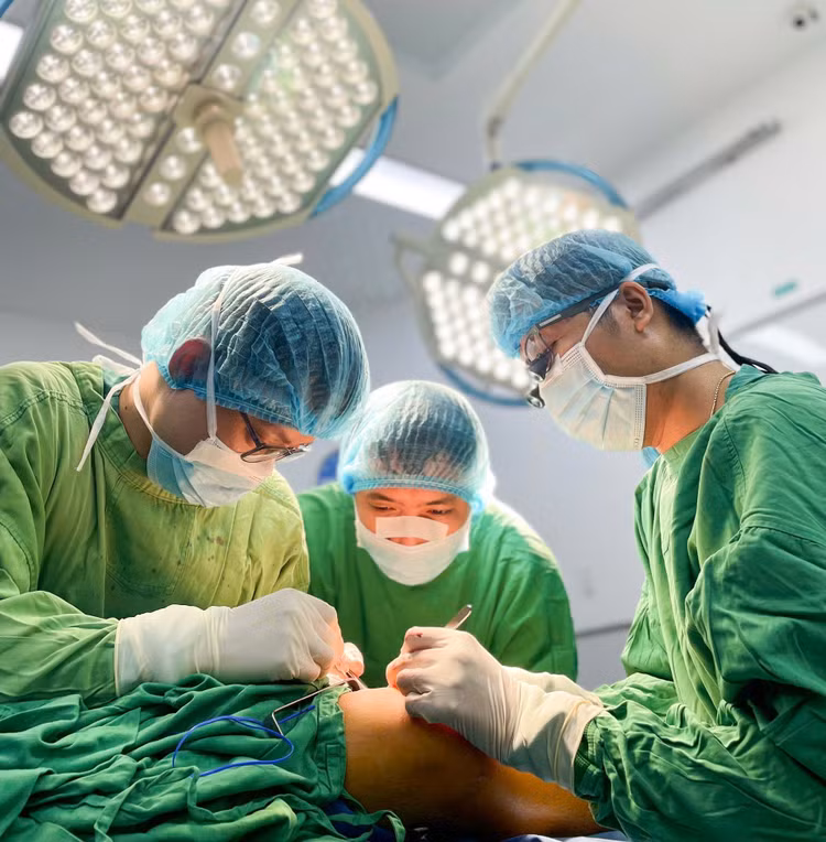 Ê-kip bác sĩ tập trung cao độ để nối đoạn tĩnh mạch hiển từ chân cứu cánh tay cháu bé./ Ảnh daibieunhandan.vn