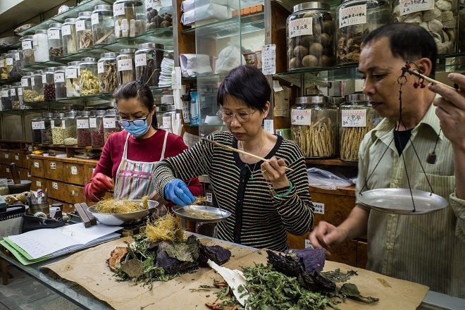 Chủ hàng cân dược liệu Trung y trong một hiệu thuốc ở Hong Kong. Ảnh: NY Times