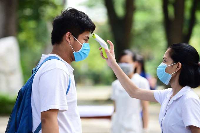 Thí sinh được kiểm tra thân nhiệt tại điểm thi THPT Chu Văn An, Hà Nội. Ảnh: Giang Huy