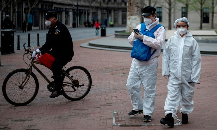 Người Trung Quốc mặc đồ bảo hộ trên đường phố Vũ Hán ngày 1/4. Ảnh: AFP.