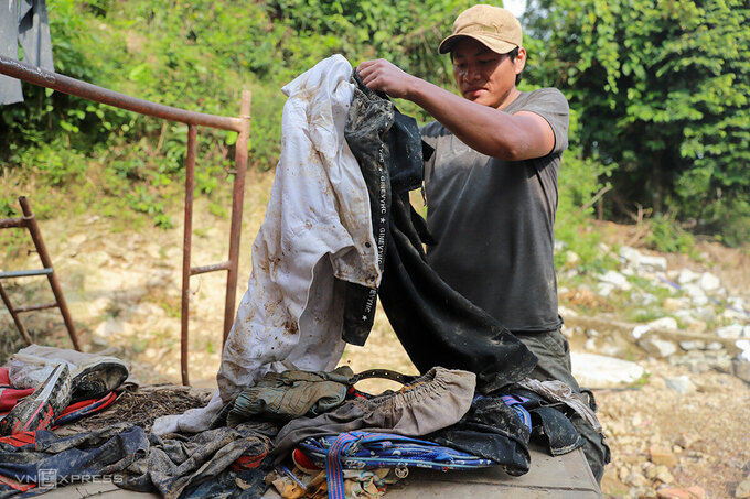 Anh Nhua gom số quần áo còn sót lại sau lũ, tính giặt lại để cho gia đình mặc. Ảnh: Nguyễn Đông.