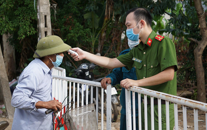 Công an đo thân nhiệt người vào khu cách ly phố Nam Bắc, phường Quảng Vinh - nơi phát hiện ca bệnh 748. Ảnh: Lê Hoàng.