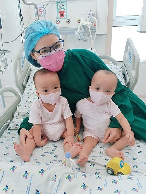 Hai bé chụp ảnh cùng mẹ trong lần đầu tập đeo khẩu trang. Ảnh: Bệnh viện cung cấp.