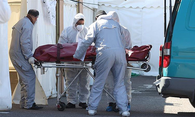 Nhân viên đưa thi thể người chết vì Covid-19 đến nhà xác tạm thời ở bãi đỗ xe ở thành phố Birmingham, Anh, hôm 21/4. Ảnh: Reuters.