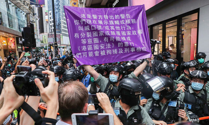 Cảnh sát giơ lá cờ có dòng chữ cảnh báo vi phạm luật an ninh ở Vịnh Causeway hôm nay. Ảnh: SCMP.