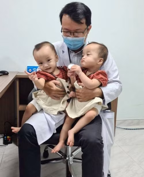 Trúc Nhi, Diệu Nhi tinh nghịch, làm mặt xấu khi ngồi trong lòng bác sĩ. Ảnh: Bệnh viện cung cấp.