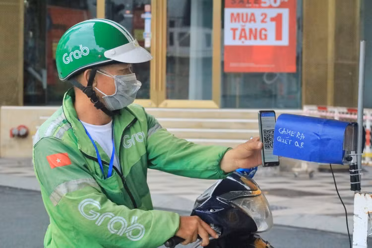 Ông Nguyễn Nhật Vũ (49 tuổi, shipper) đến chốt ngã sáu Phù Đổng và được một cán bộ công an hướng dẫn để quét mã thông qua camera tự động /// Cao An Biên