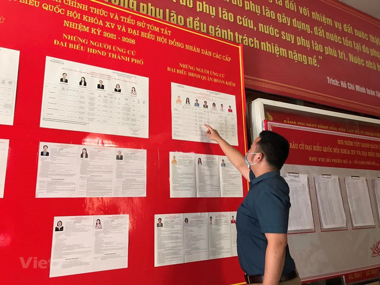 Cử tri xem xét danh sách niêm yết những người ứng cử đại Quốc hội khóa XV và Hội đồng Nhân dân các cấp nhiệm kỳ 2021-2026. (Ảnh: Xuân Quảng/Vietnam+)