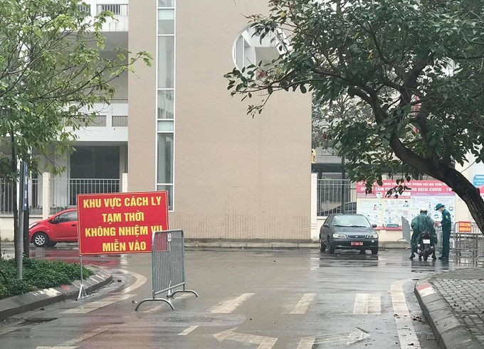 Phụ huynh tiếp tế cho con đang cách ly tại cổng trường. Ảnh: Hải Hiền.