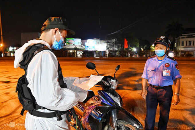 Lực lượng an ninh kiểm tra giấy tờ của người dân khi qua chốt kiểm dịch, đêm 15/2. Ảnh: Giang Huy