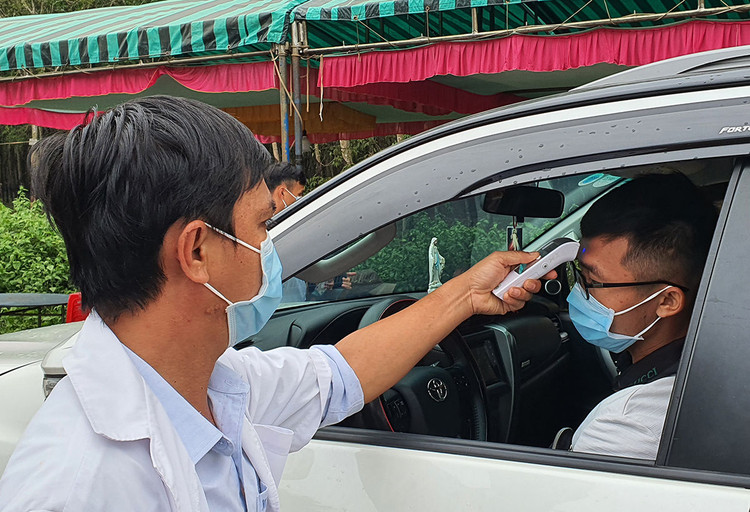 Nhân viên y tế đo thân nhiệt tài xế chạy ôtô trên quốc lộ 56 vào Bà Rịa - Vũng Tàu. Ảnh: Phong Vũ.