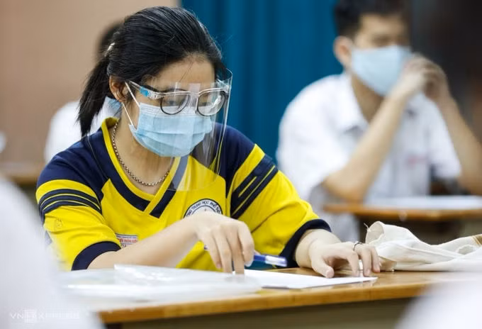 Sĩ tử cả nước thi bài tổ hợp và Ngoại ngữ ảnh 1 Một thí sinh đeo kính chắn giọt bắn trong buổi làm thủ tục dự thi tốt nghiệp THPT ở TP HCM, chiều 6/7. Ảnh: Hữu Khoa